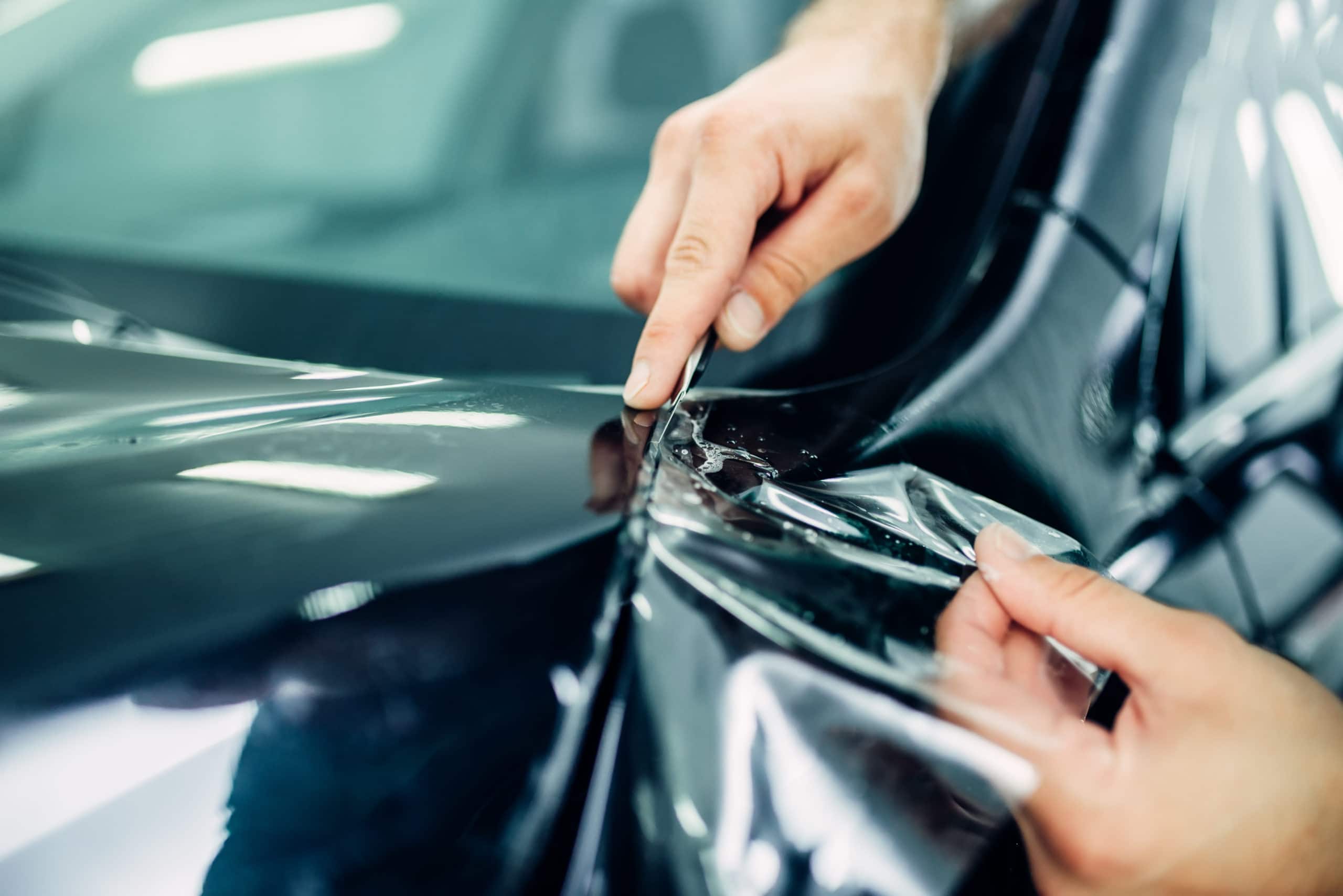 A worker applying Paint Protection Film on car's surface