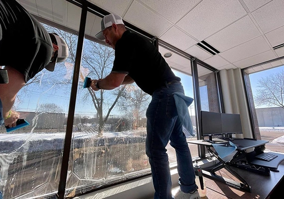 2 people installing a window tint on commercial property
