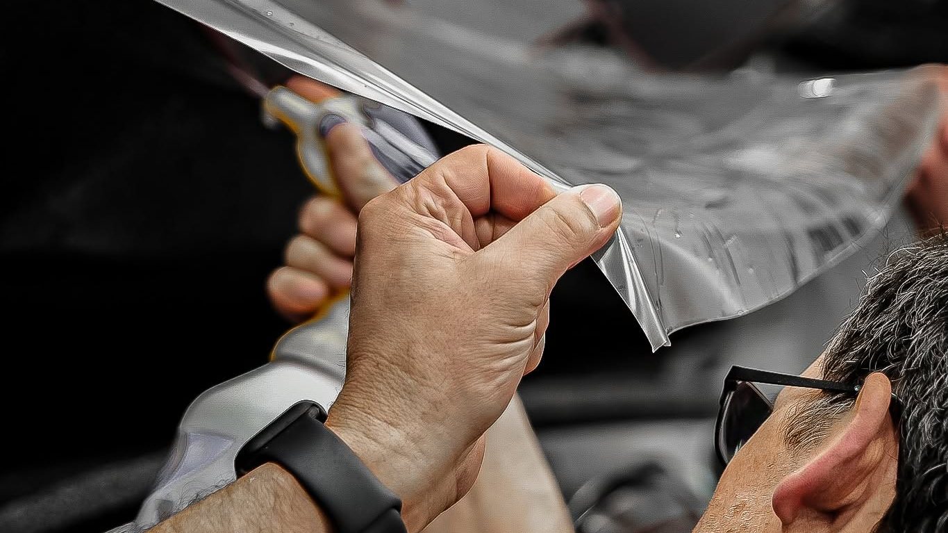 Bravo Protection installer stretching clear paint protection film into place on a vehicle